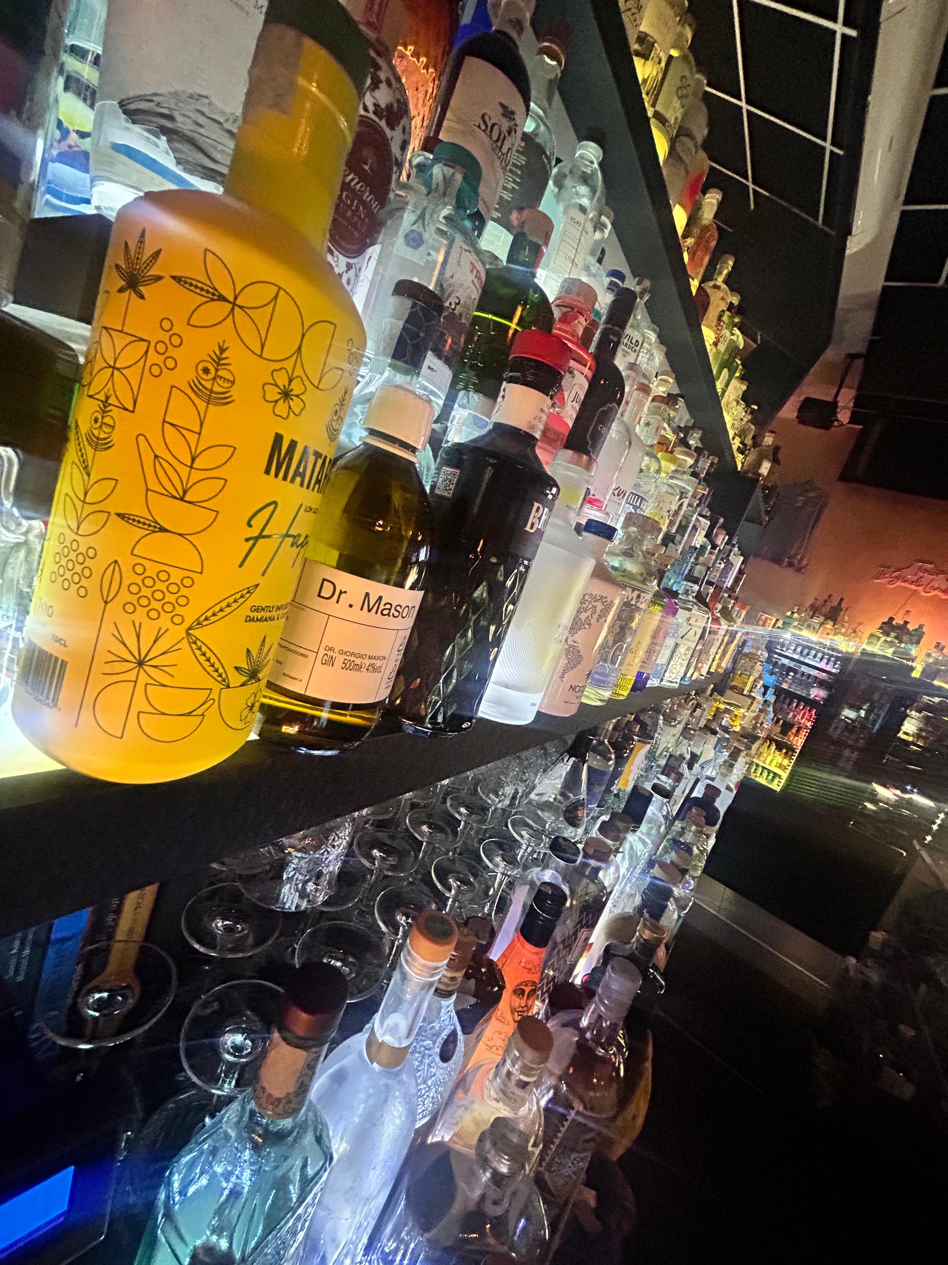 Scaffale specchiato pieno di gin, riflessi colorati